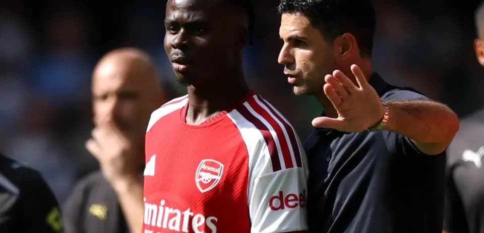 Arsenal coach discussing strategy with player on pitch