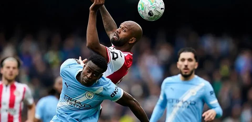 Manchester City player challenging Brentford player for ball