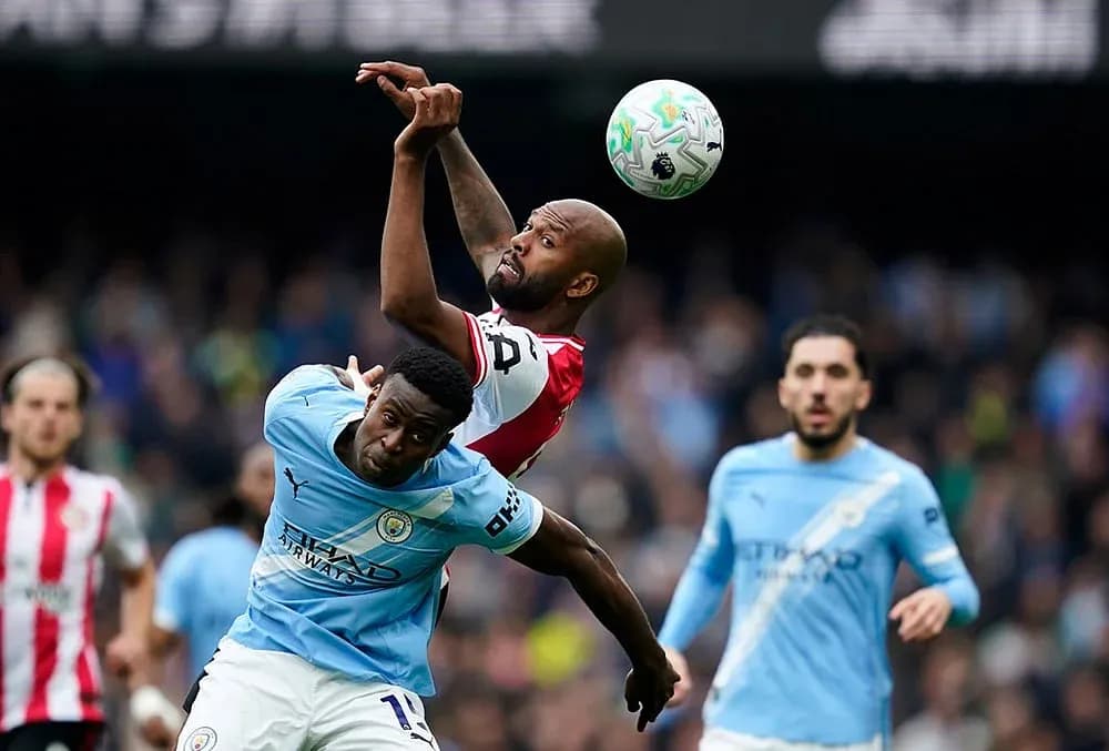 Manchester City player challenging Brentford player for ball