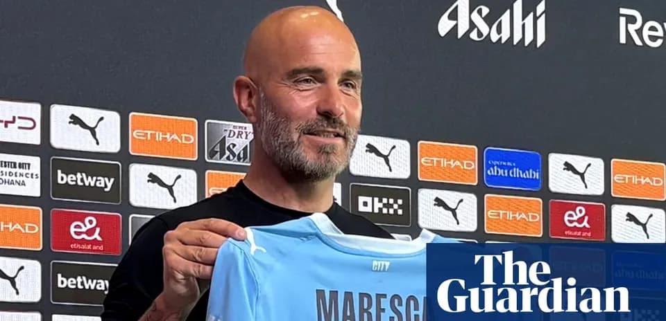 Coach holding a Manchester City jersey at press conference
