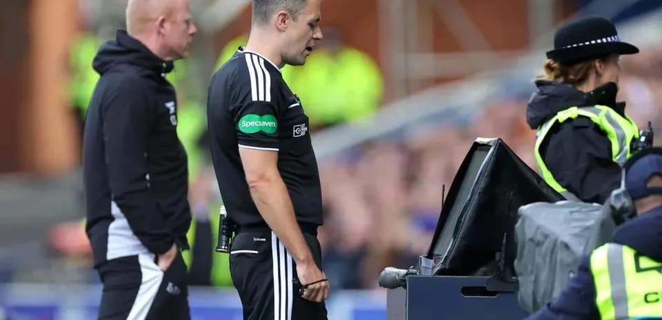 Referee reviewing VAR decision with assistant nearby