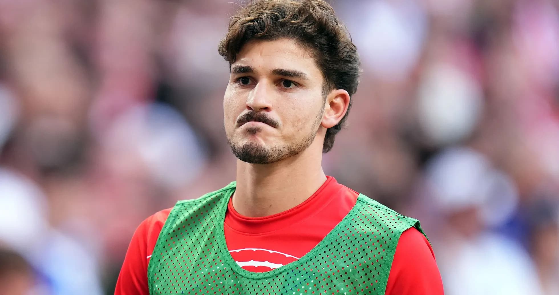 Player in green training bib on sidelines
