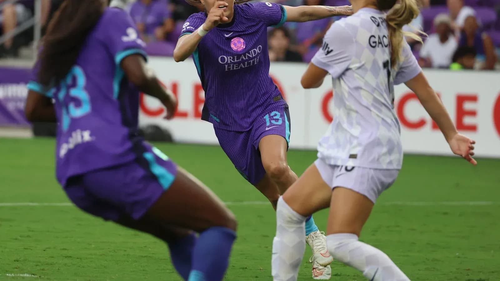 Orlando Pride player dribbling past Portland Thorns players