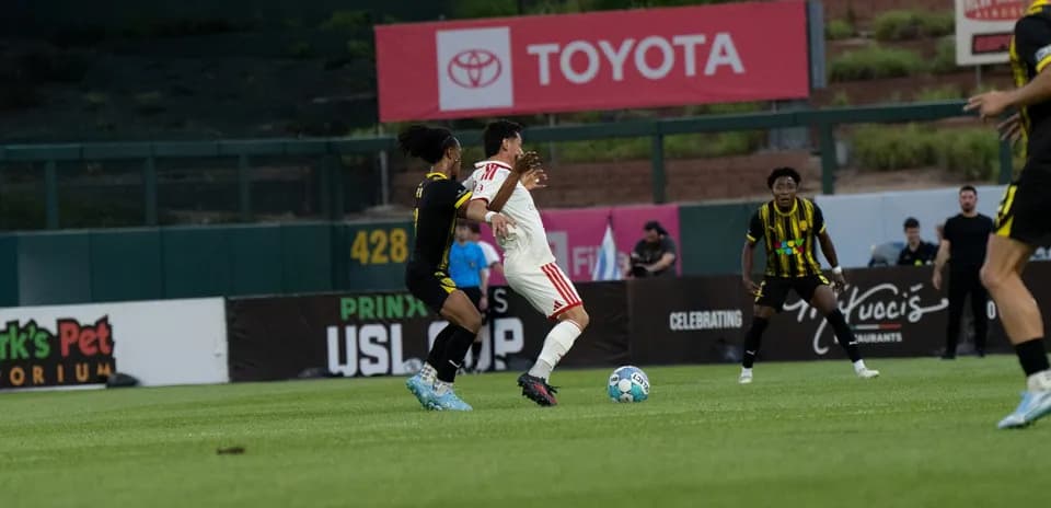 Players battling for the ball in USL Cup match