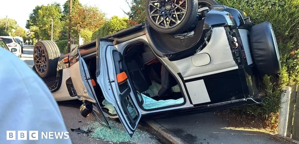 Upside-down sports car on roadside with broken glass