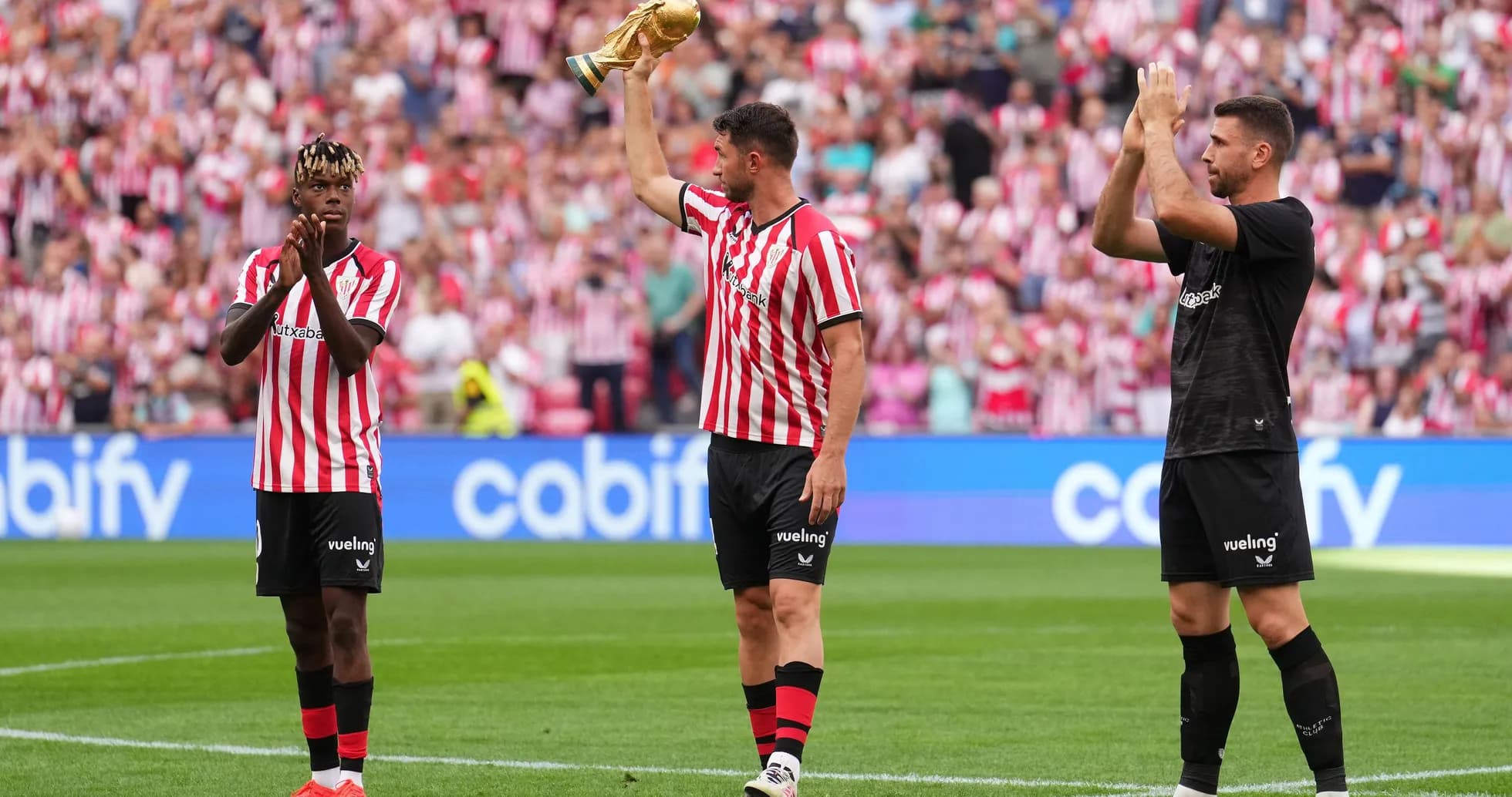 Athletic Bilbao players celebrating with trophy and applauding fans