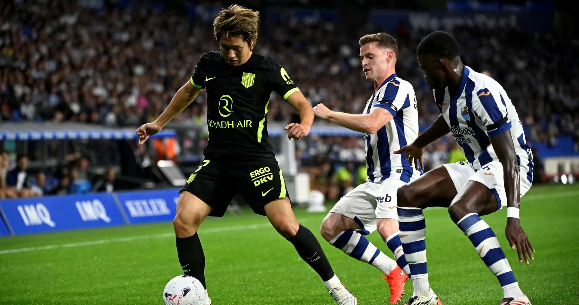 Atletico Madrid player dribbling past Real Sociedad opponents