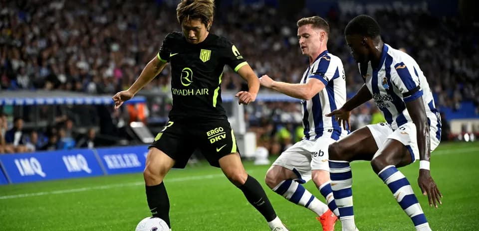 Atletico Madrid player dribbling past Real Sociedad opponents