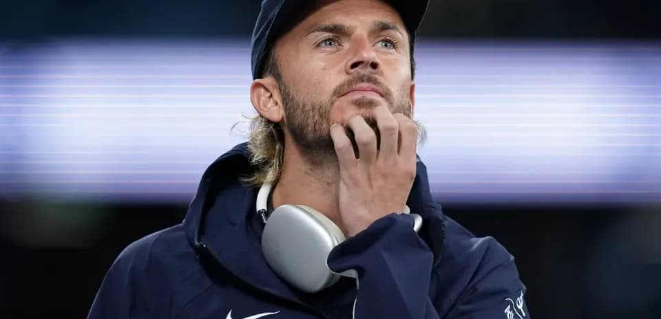 Man in jacket and cap looking thoughtfully