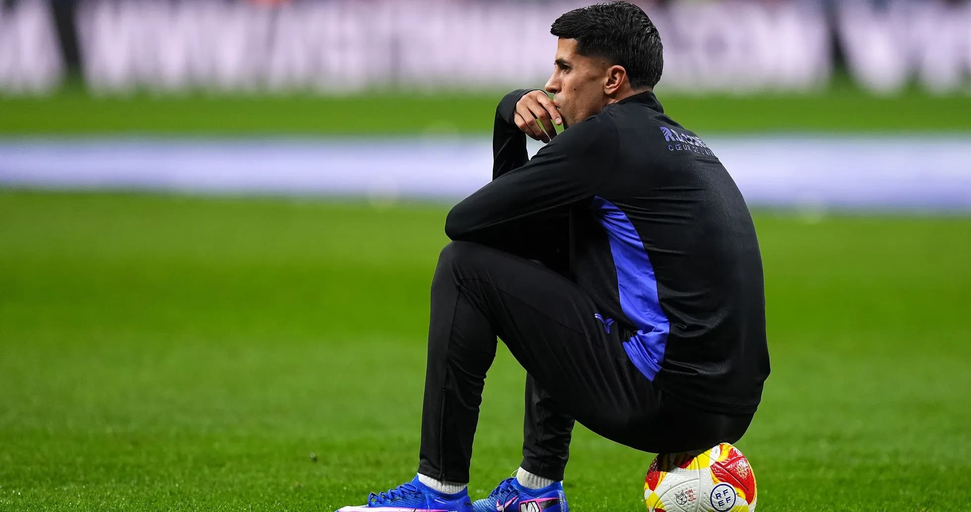 Coach sitting on the pitch with a ball