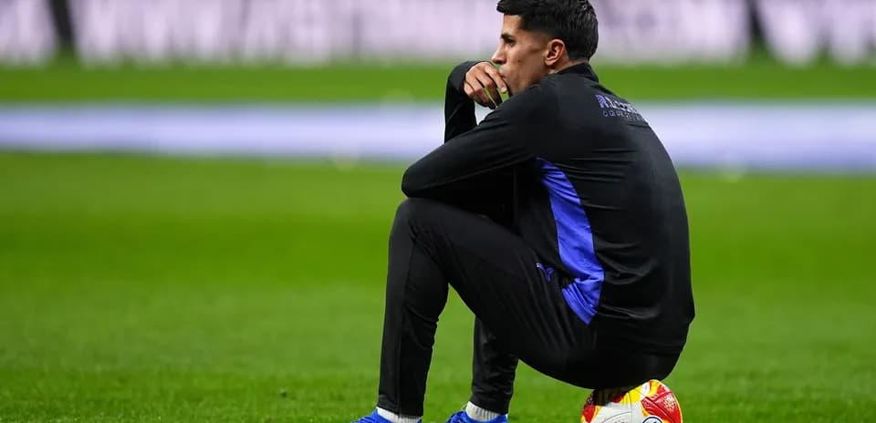 Coach sitting on the pitch with a ball