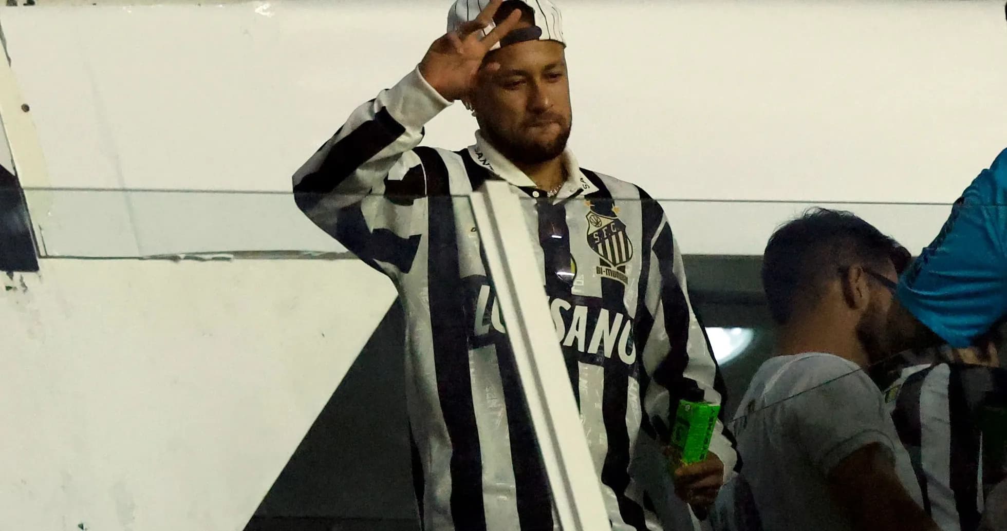 Man waving in Santos FC jersey at stadium