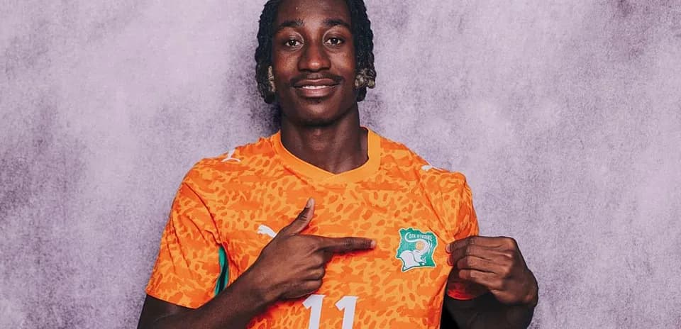 Player in orange jersey pointing at Ivorian crest