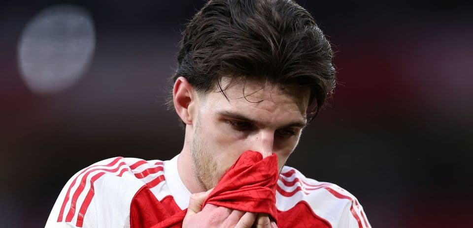 Player holding jersey close to face on pitch