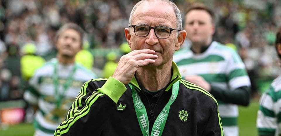 Manager walking on pitch with Celtic supporters in background
