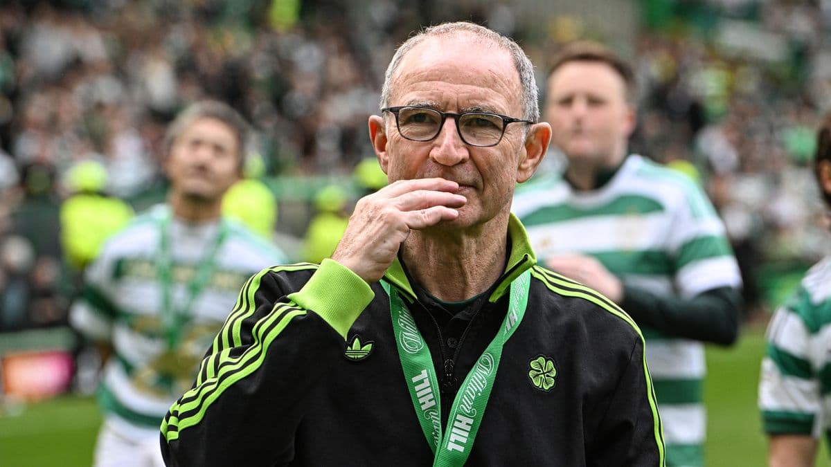 Manager walking on pitch with Celtic supporters in background