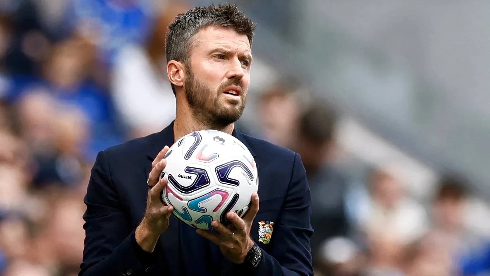 Coach holding a soccer ball on the sideline