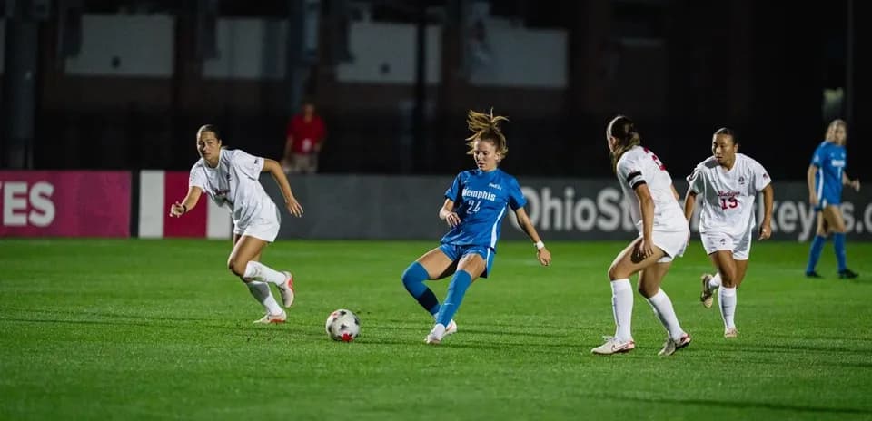 Player in blue dribbling the ball past defenders