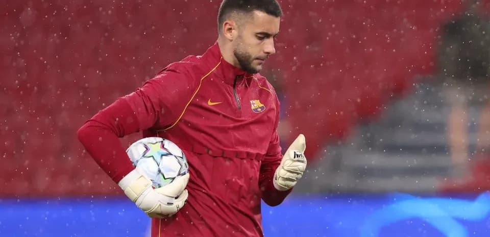 Goalkeeper in red jersey holding a soccer ball