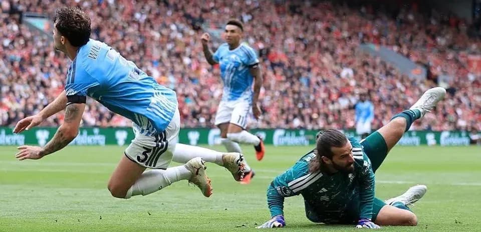 Player falling near goalkeeper during football match
