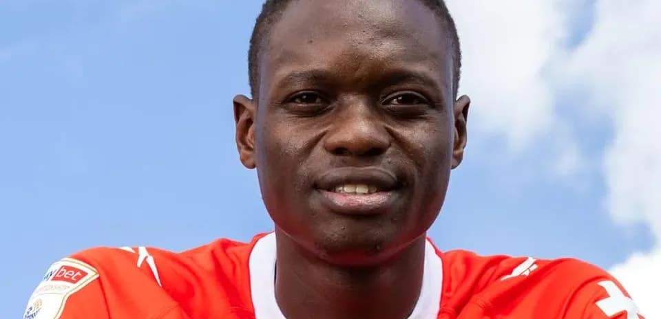 Player posing in red team jersey against blue sky