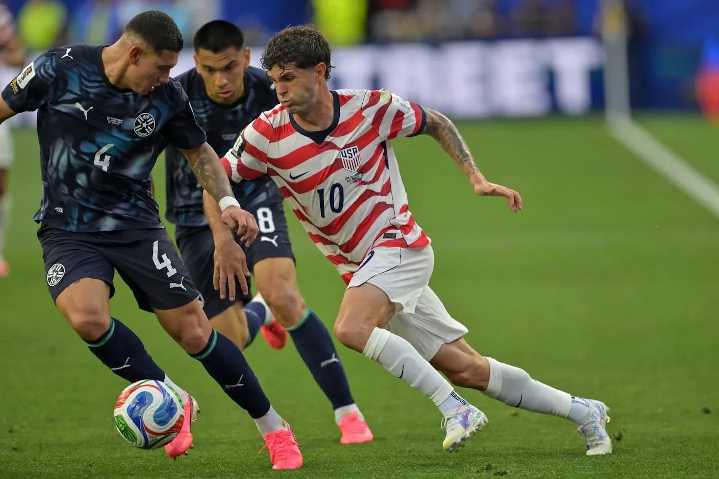 Christian Pulisic dribbling past two defenders during match