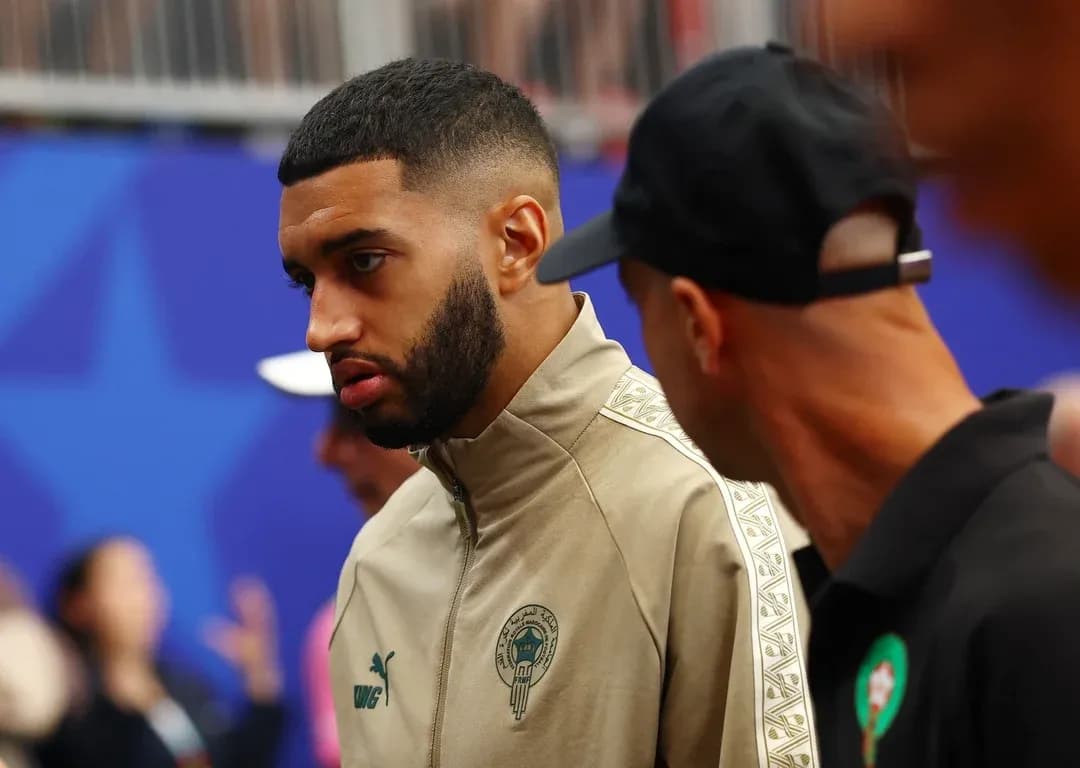 Player in team tracksuit talking with another person