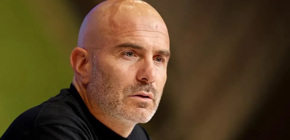 Coach speaking at a press conference table