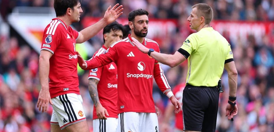 Manchester United players arguing with the referee