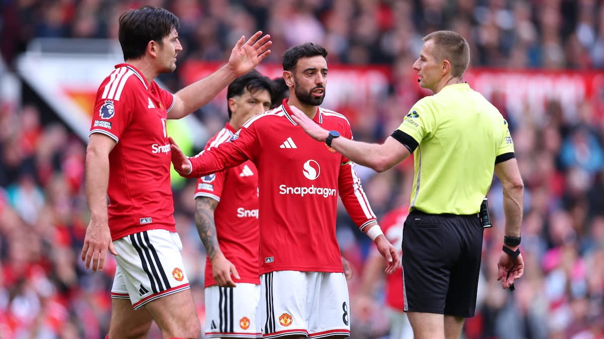 Manchester United players arguing with the referee