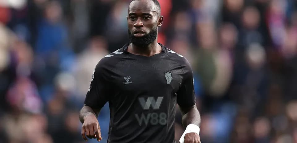 Player in black kit walking on the field