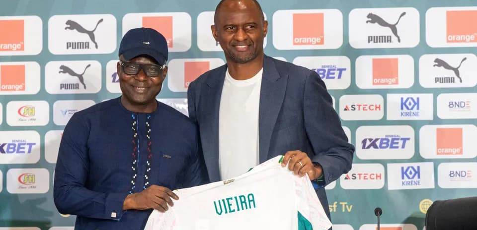 Two men holding a jersey at a press conference
