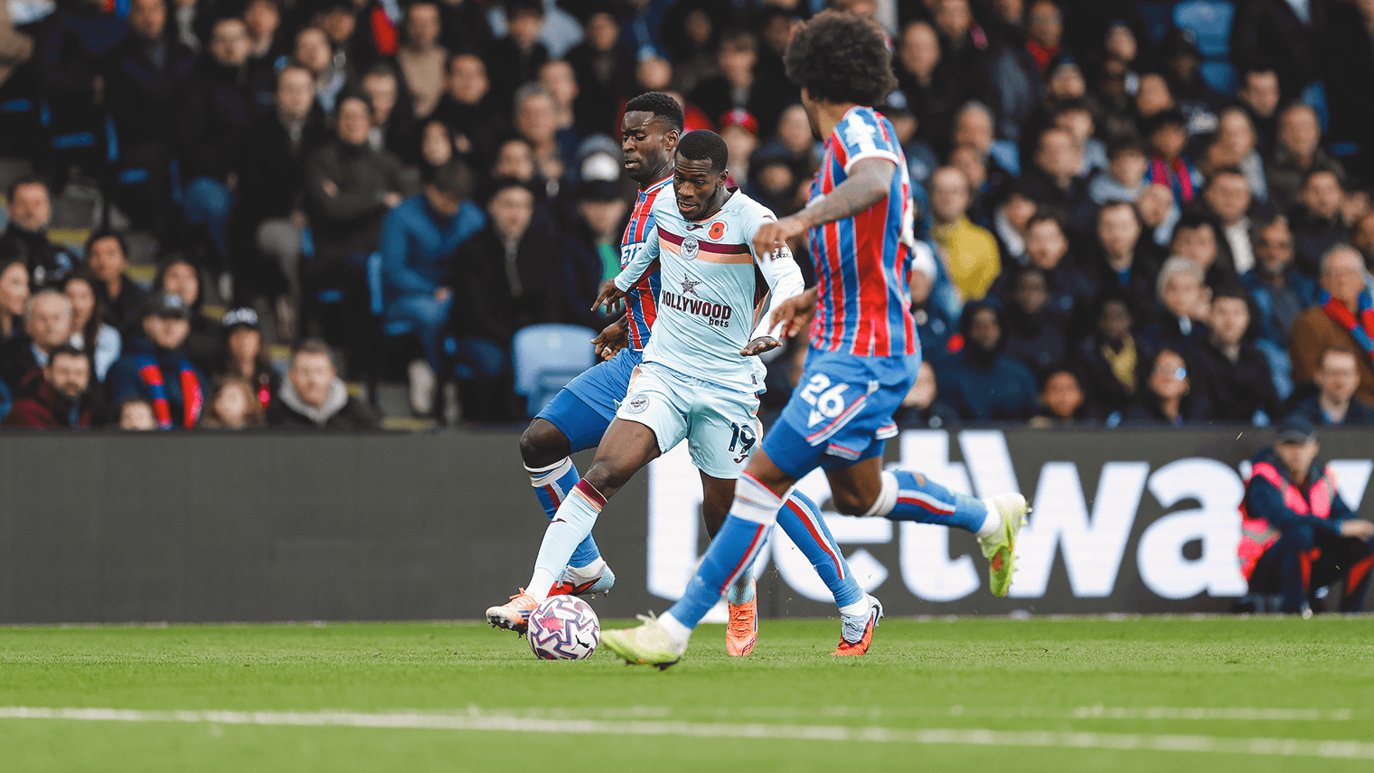 Brentford player dribbling against Crystal Palace opponents