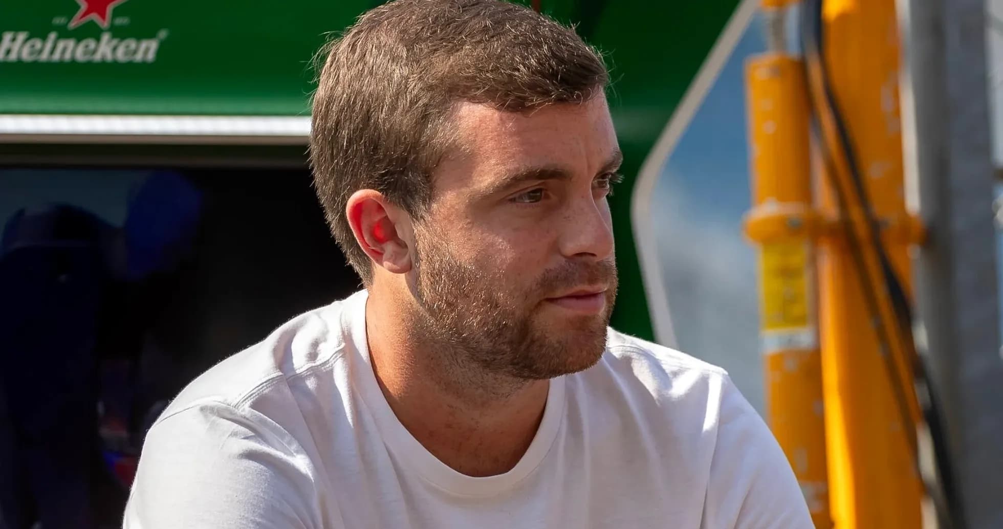 Man sitting near racing team equipment outdoors