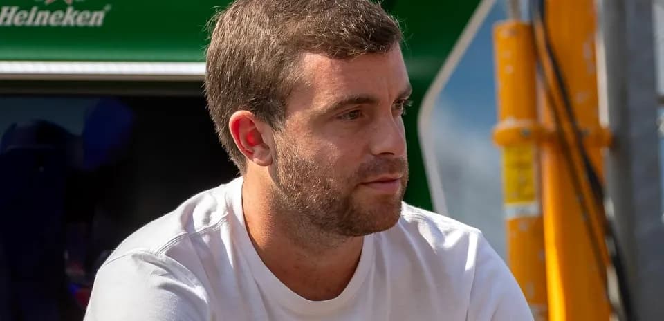 Man sitting near racing team equipment outdoors