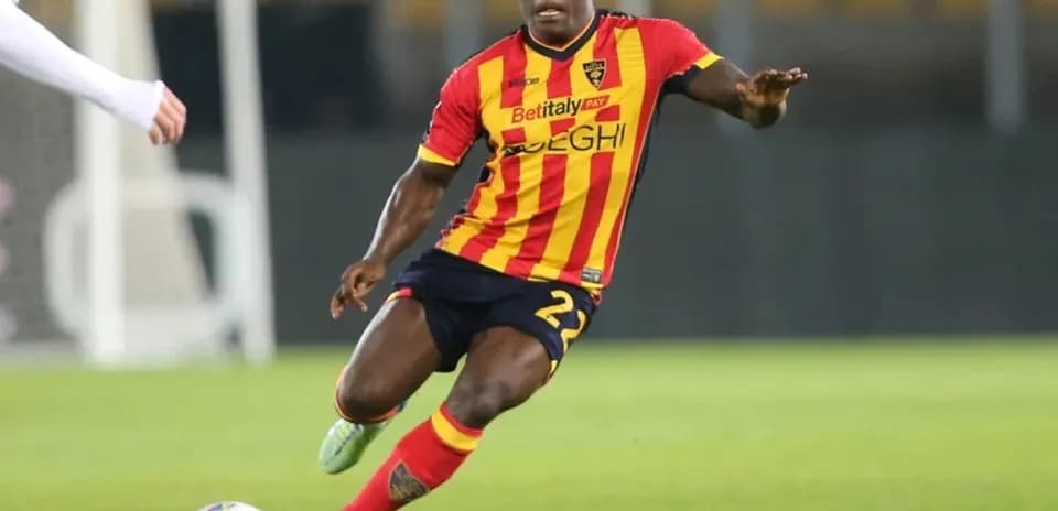 Player in red and yellow kit dribbling ball on field