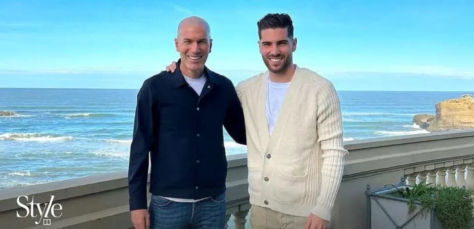 Two men posing together by the ocean