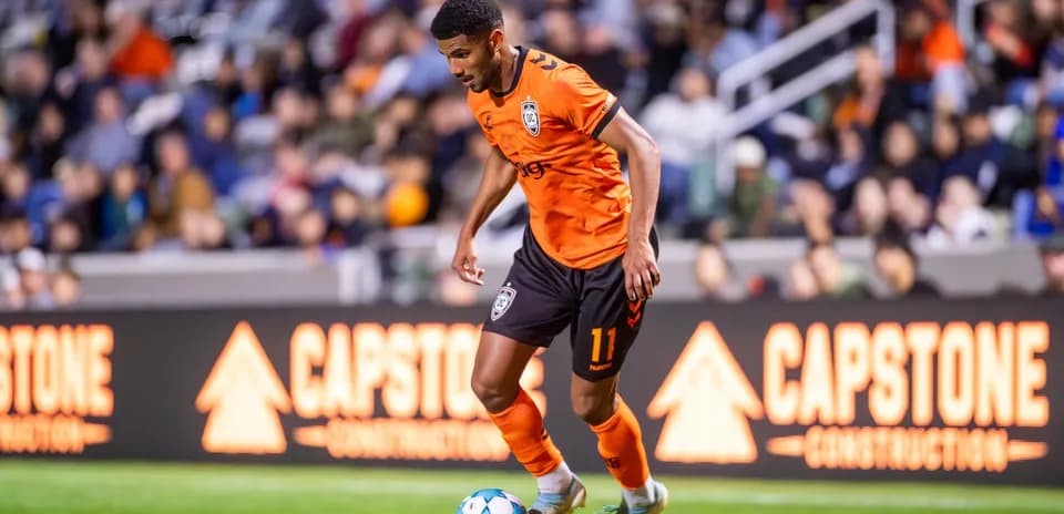 Player dribbling the ball in orange kit