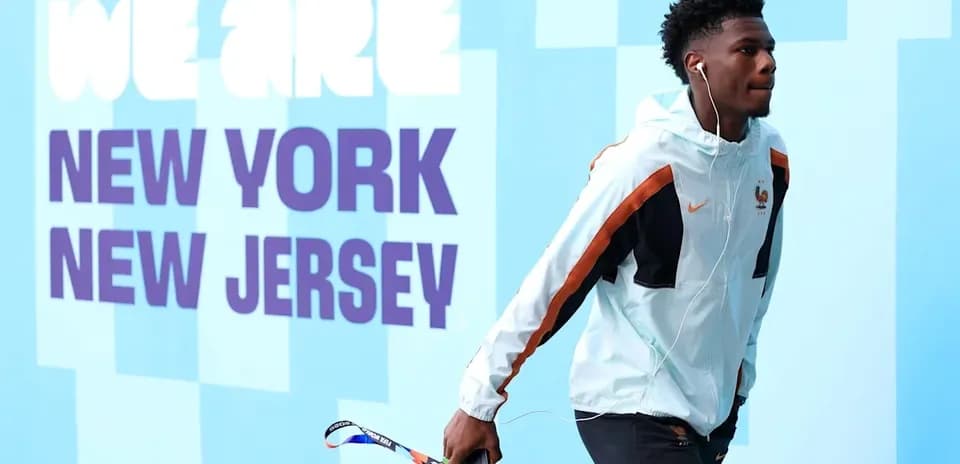Player walking with headphones near promotional wall