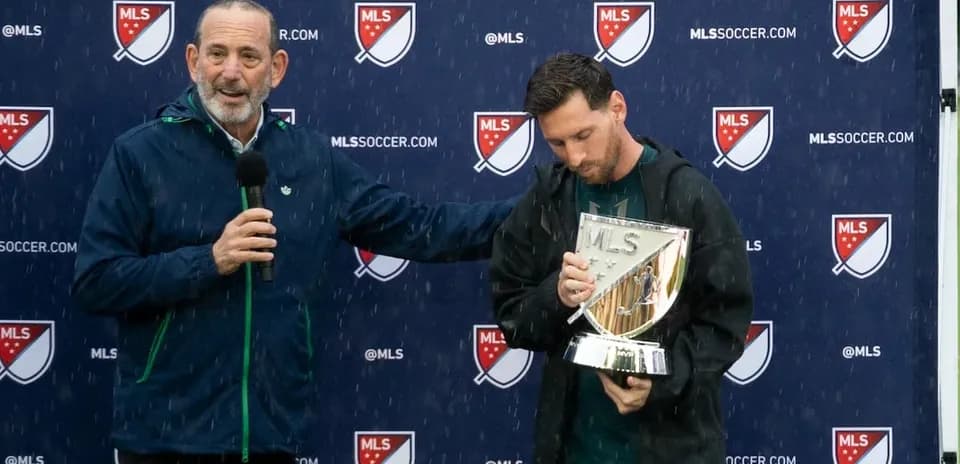 MLS official presenting trophy to player in rain