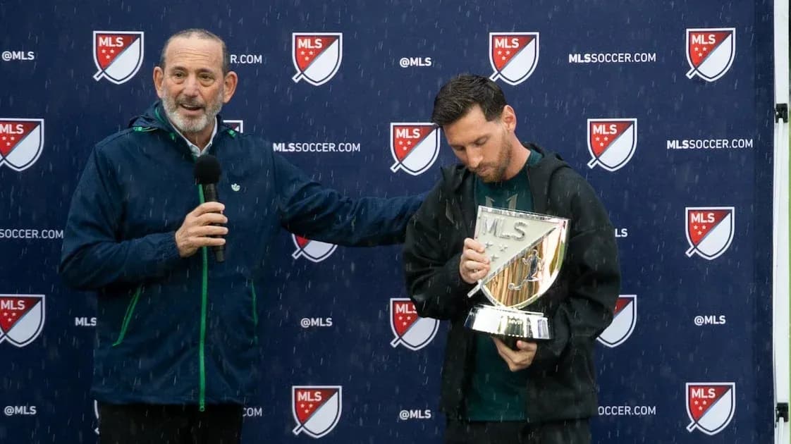 MLS official presenting trophy to player in rain