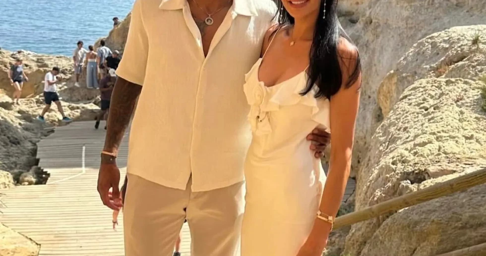 Couple posing near rocky coastline with ocean background