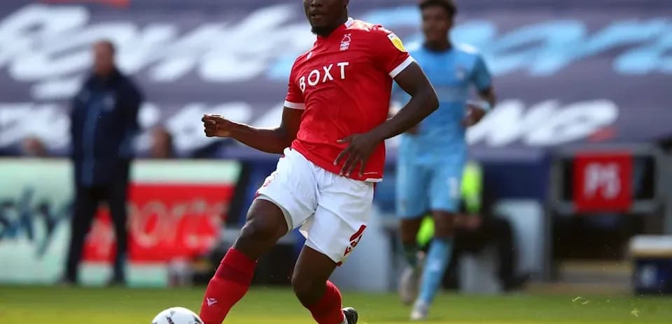 Player in red kit dribbling the ball on field