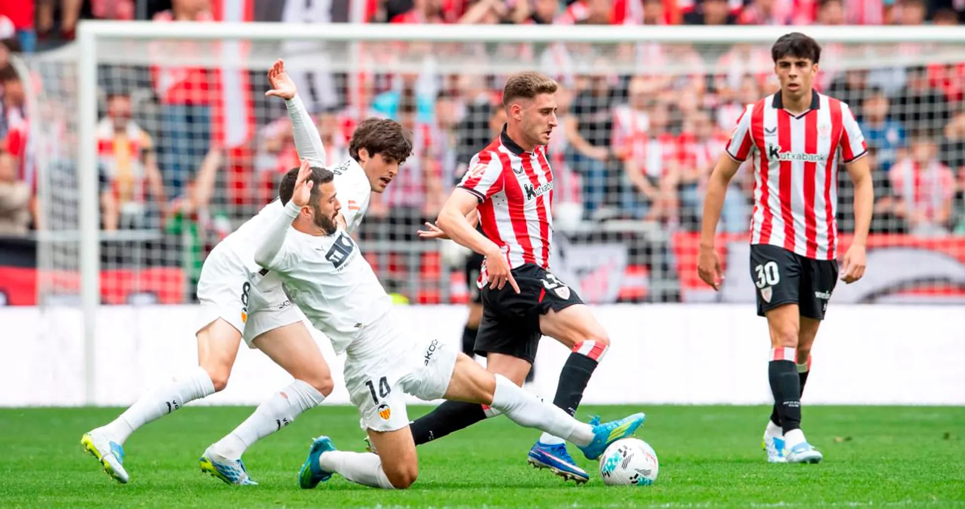 Athletic Club player challenging Valencia player for the ball