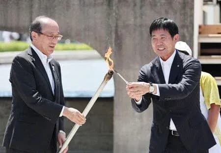Two officials lighting a torch at ceremony