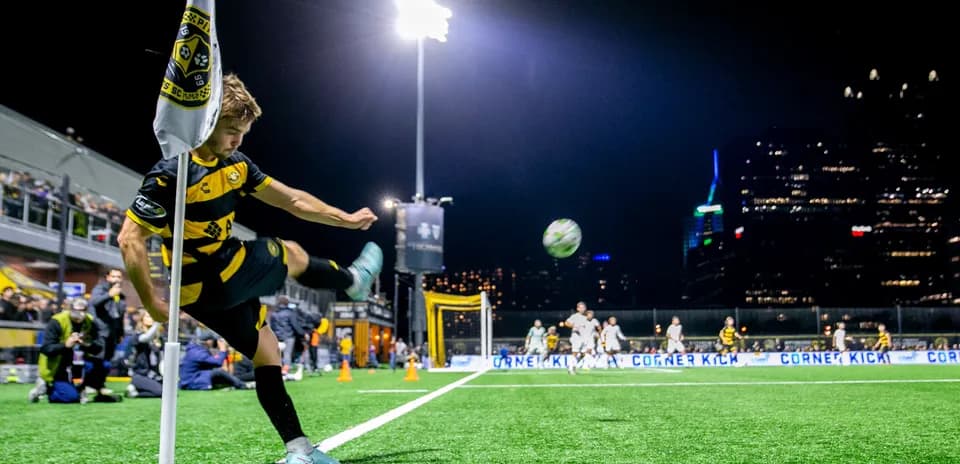 Player taking a corner kick at night