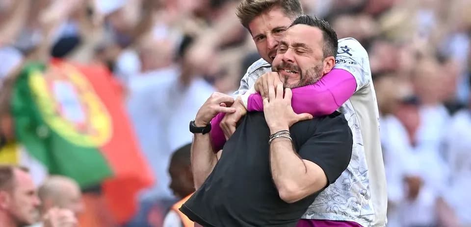Two coaches celebrating enthusiastically on the sidelines
