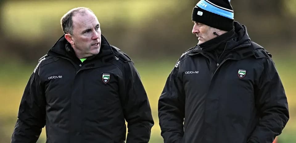 Two coaches talking on a training field