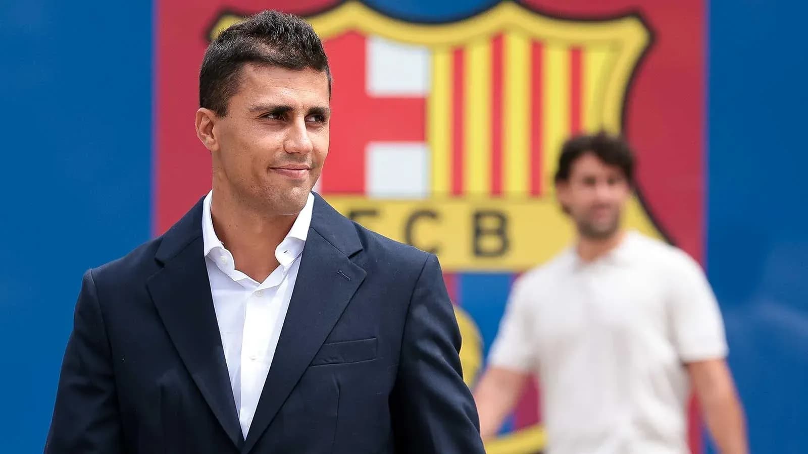 Player in suit in front of FC Barcelona logo