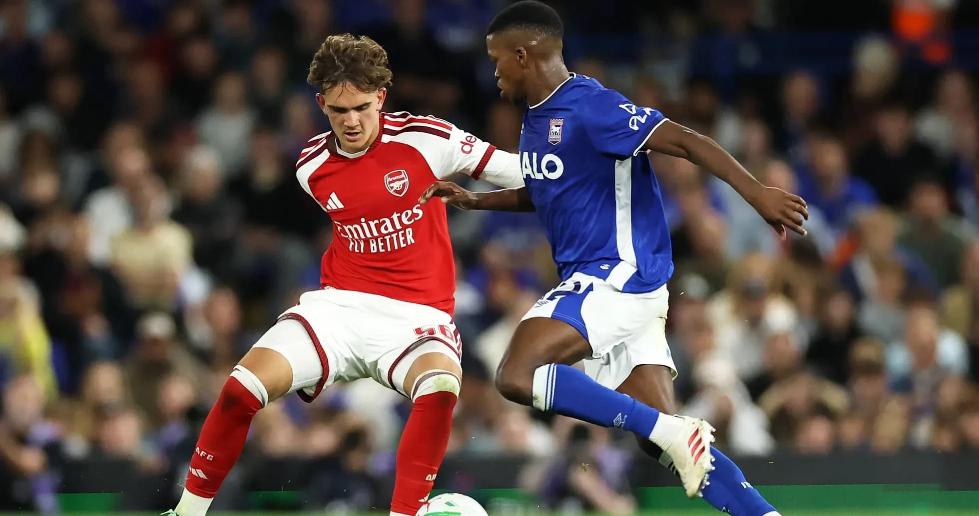 Player in red and player in blue competing for the ball
